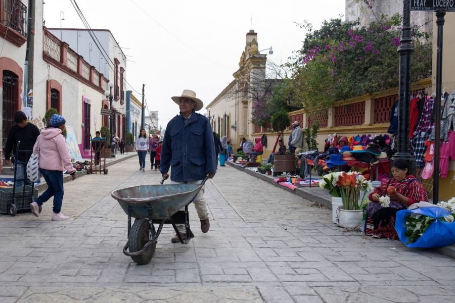 People head to work in the early morning hours in Tlaxiaco including a man pushing a wheelbarrow in the nearground.